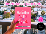 Pink book titled 'The Marketing Burn Book' held by a hand with a cityscape background